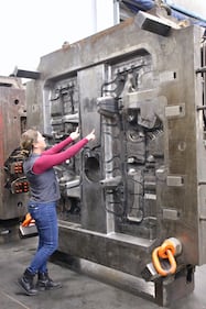 Janel Rowbotham stands in front of a large metal plate with her arms outstretched.